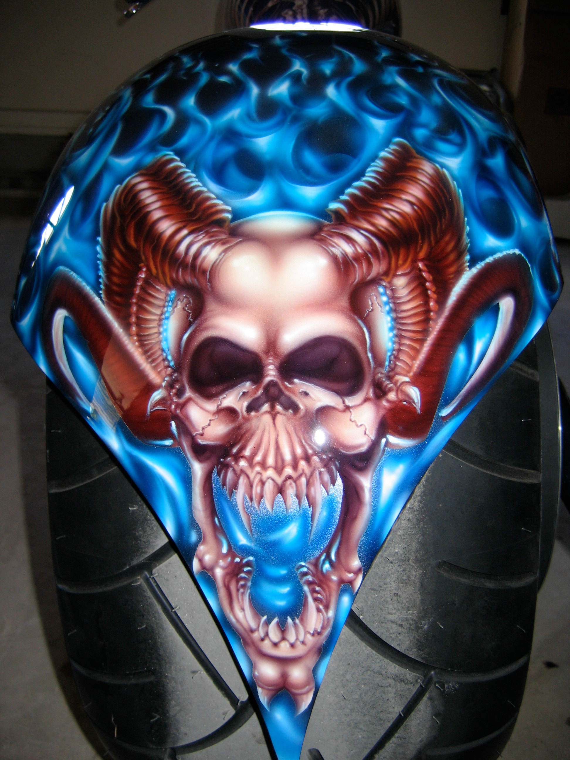 Devil's Advocate — front fender overhead, horned devil skull dead-on in blue flames