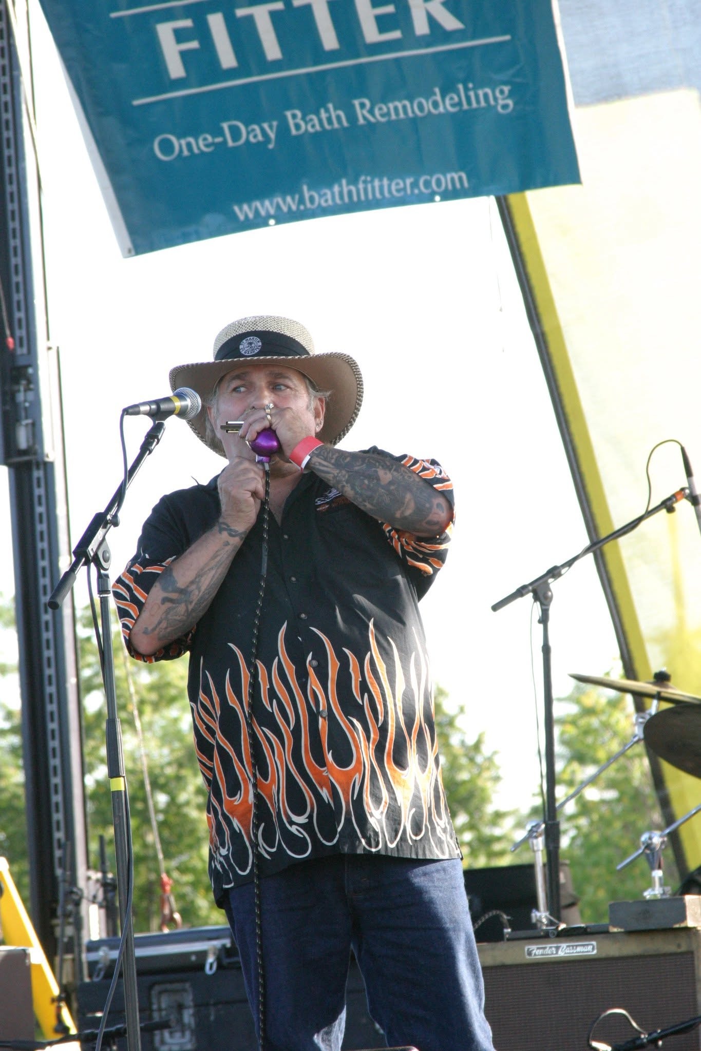 2006 Chick-N-Wing Festival — tattooed harmonica player performing on stage under Bath Fitter banner