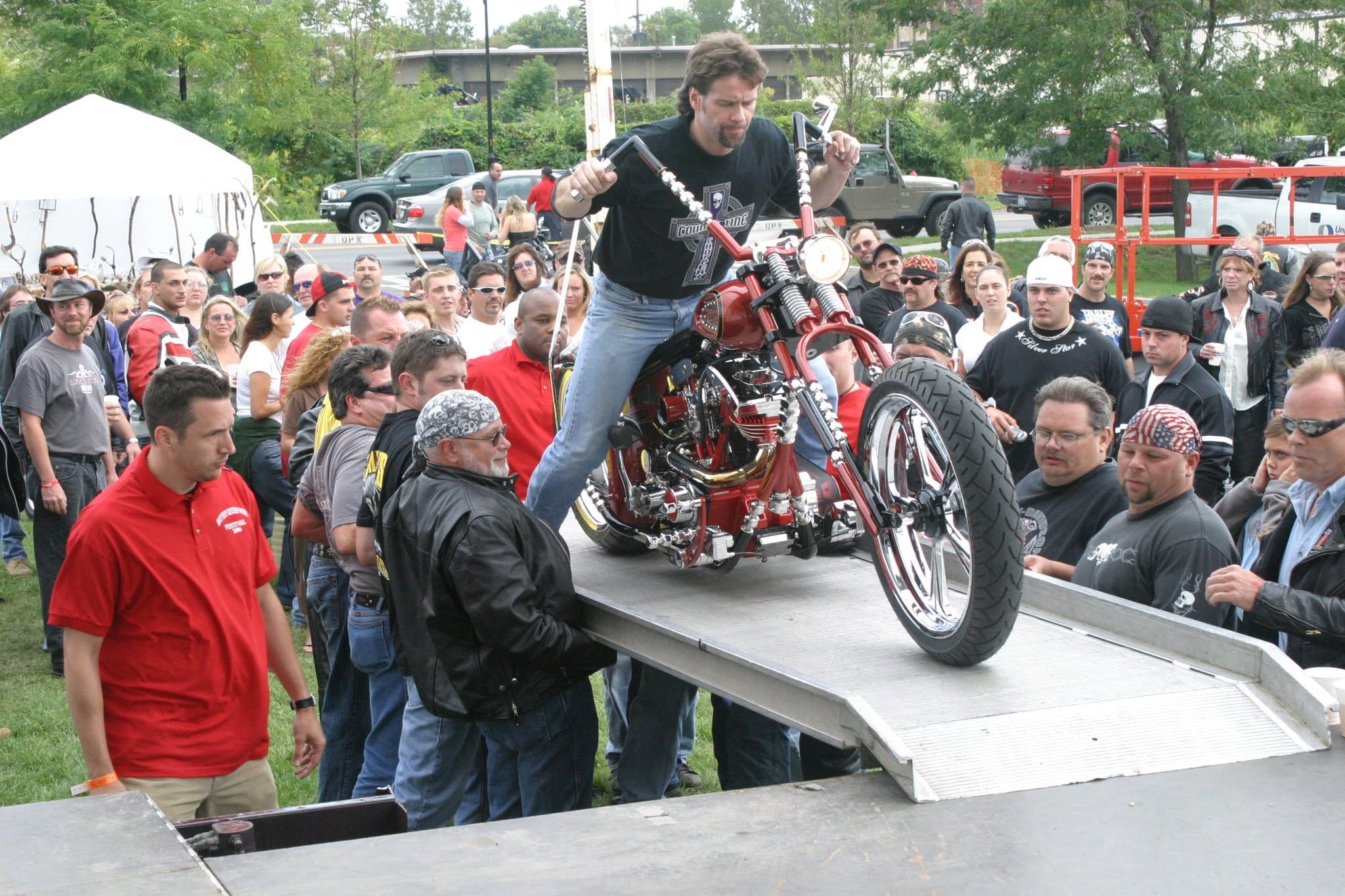 2006 Chick-N-Wing Festival — builder standing on red custom chopper riding it down stage ramp to crowd