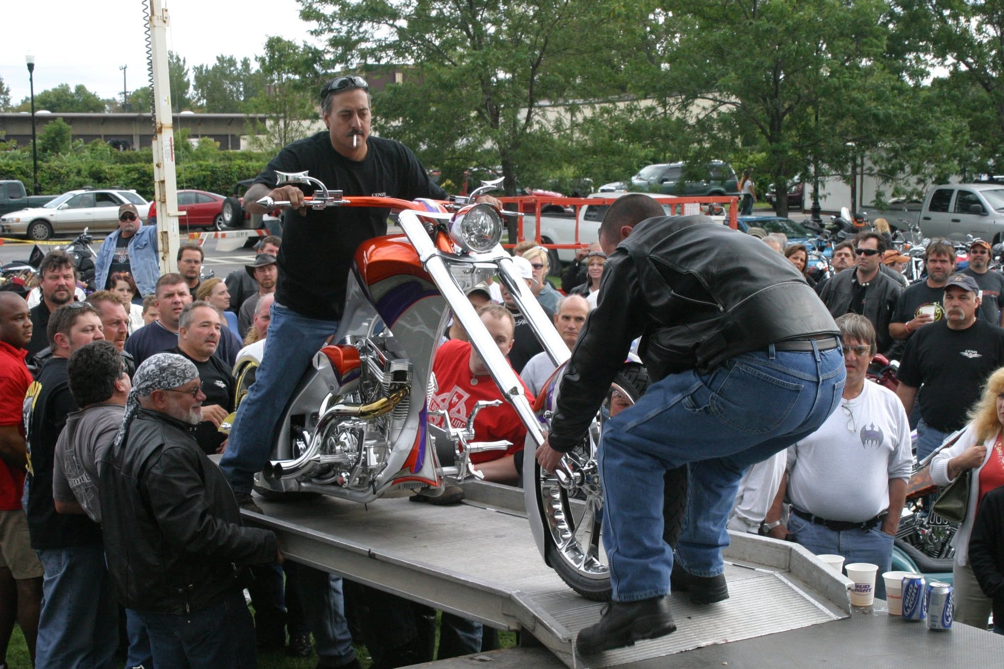 2006 Chick-N-Wing Festival — builder standing on orange and white custom chopper on stage ramp with crowd
