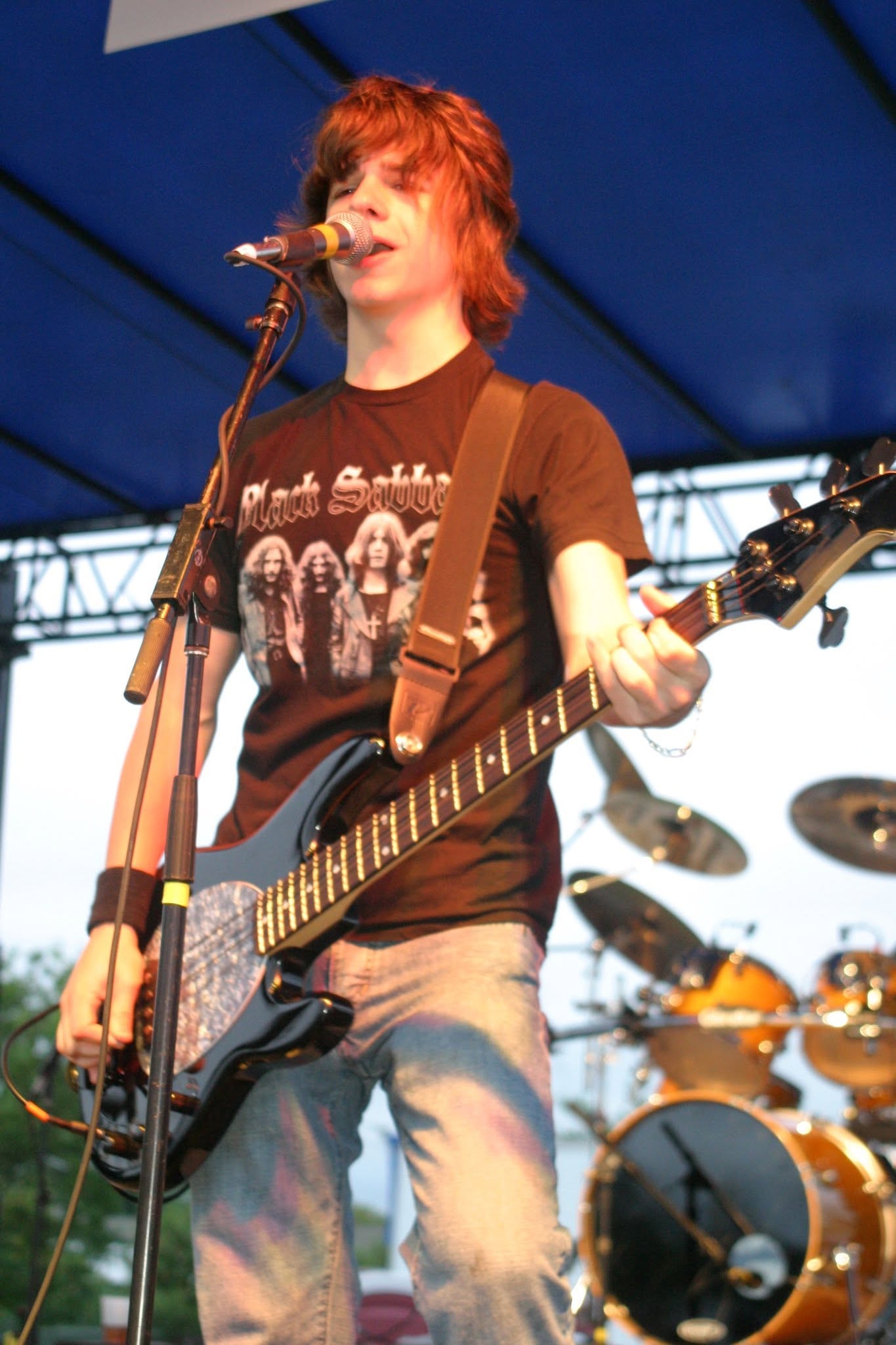2006 Chick-N-Wing Festival — young bassist in Black Sabbath shirt performing on stage under blue tent