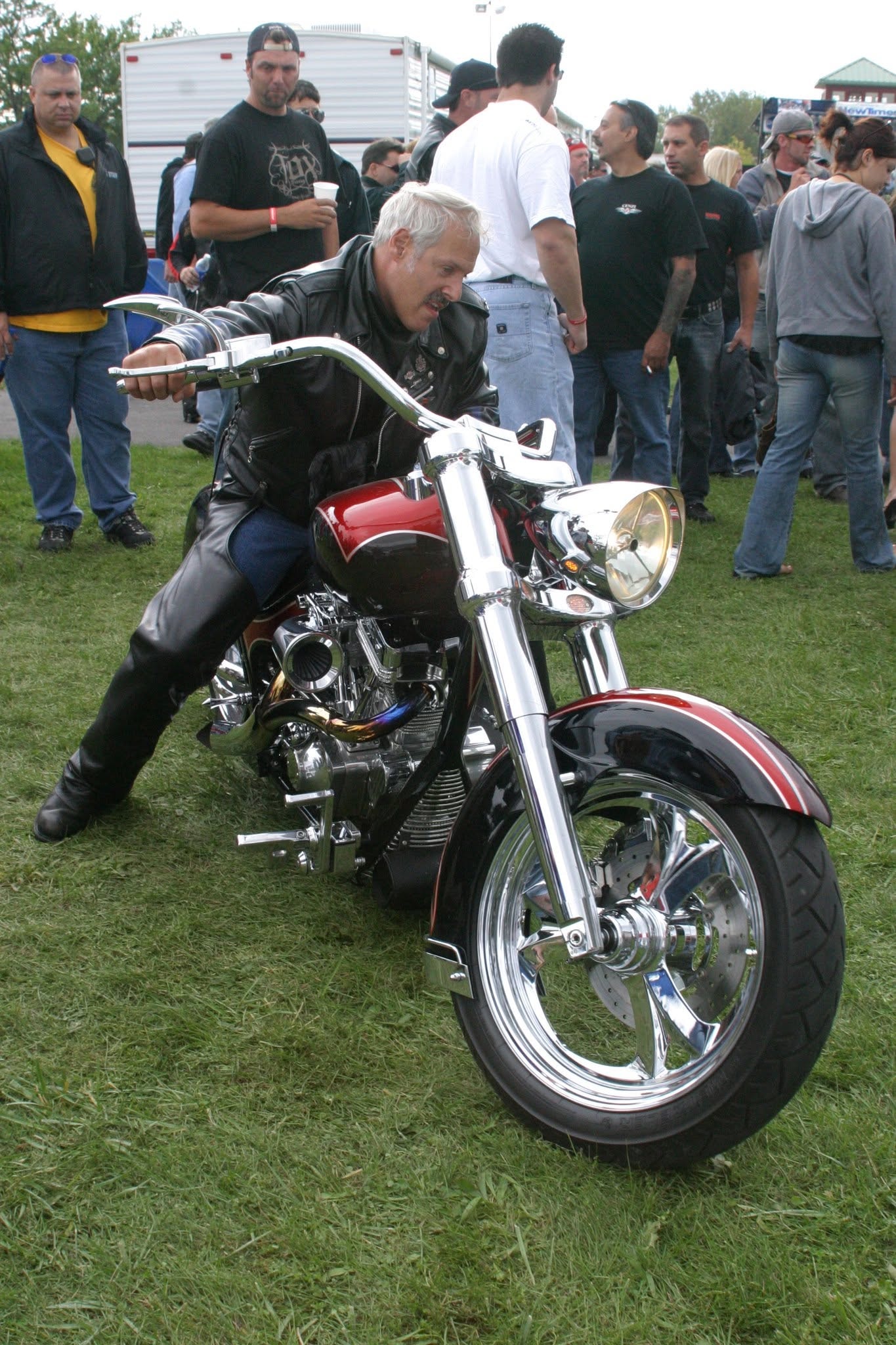 2006 Chick-N-Wing Festival — rider leaning over red and chrome custom chopper on festival grass