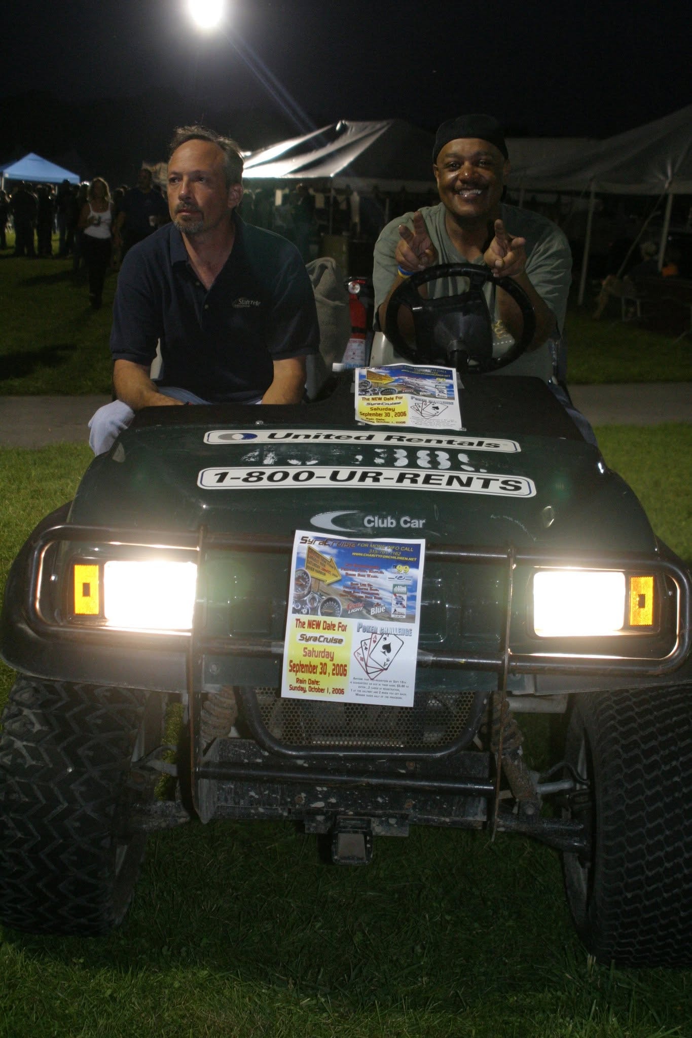 2008 Chick-N-Wing Festival — two men riding United Rentals golf cart at night