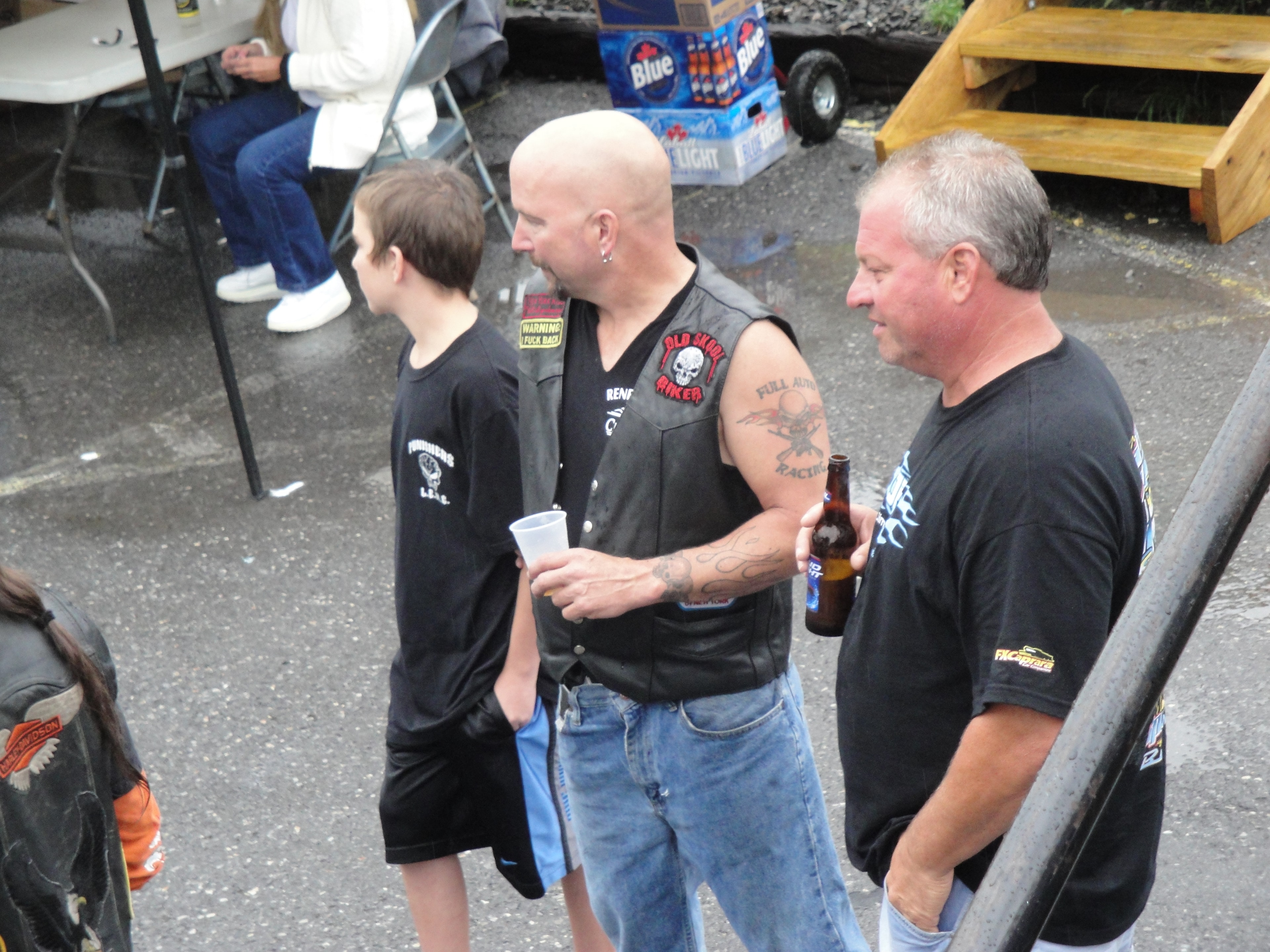 Higie's Iron Horse Saloon Summer BBQ Series — bald man in leather vest with kid and friend in parking lot