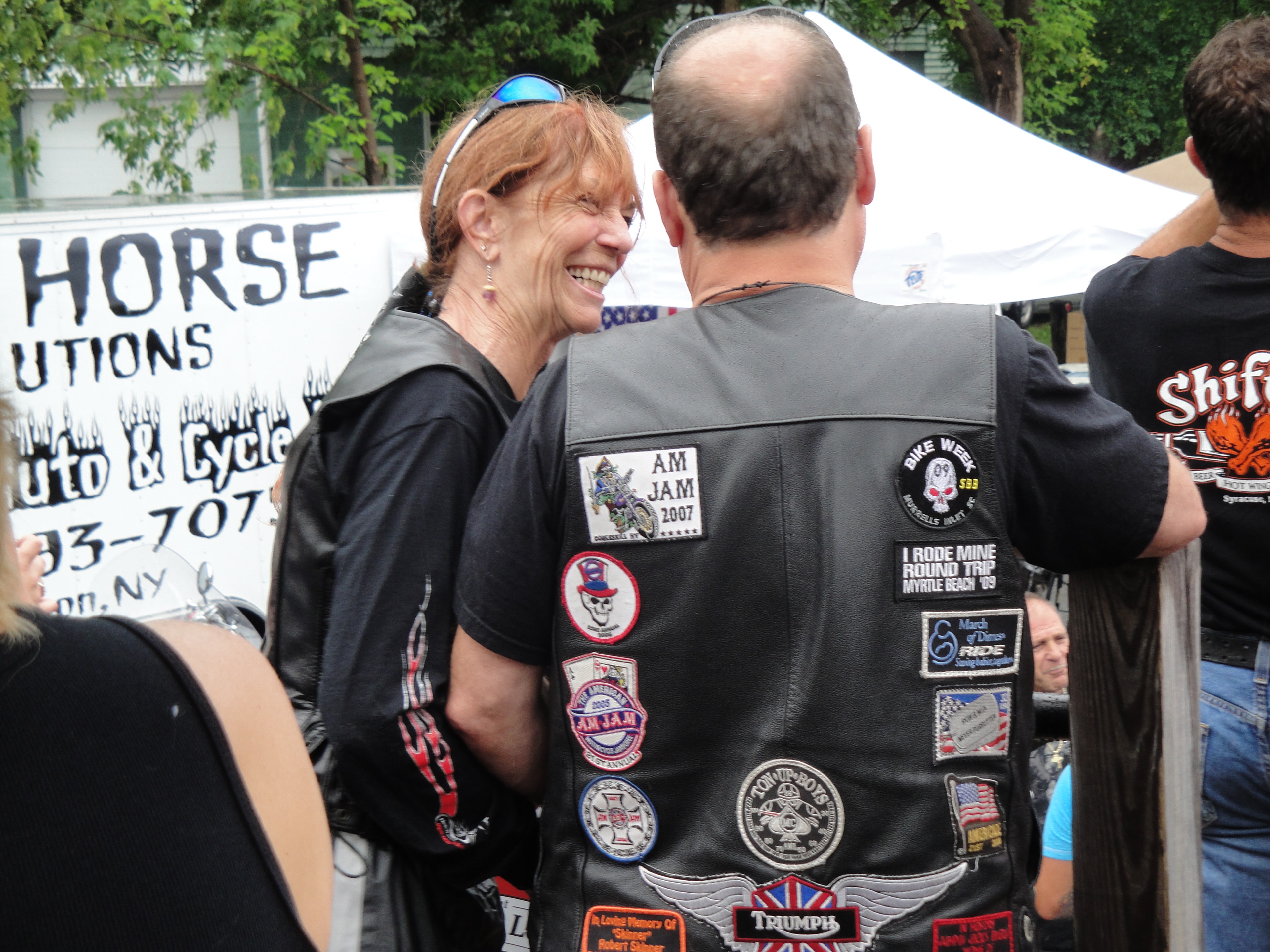 Higie's Iron Horse Saloon Summer BBQ Series — woman smiling at man with biker patches on leather vest