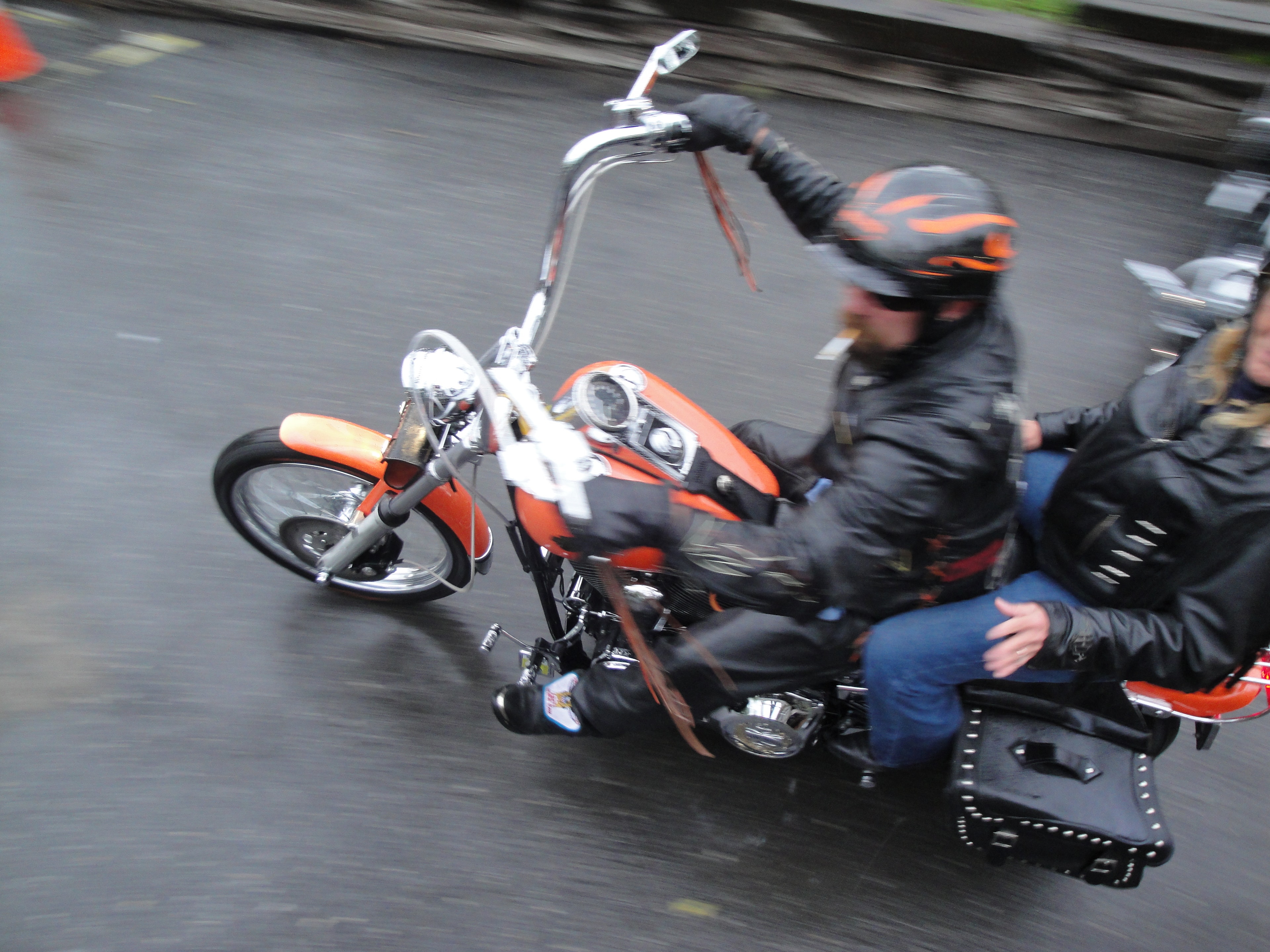 Higie's Iron Horse Saloon Summer BBQ Series — orange chopper with two riders in motion on wet pavement