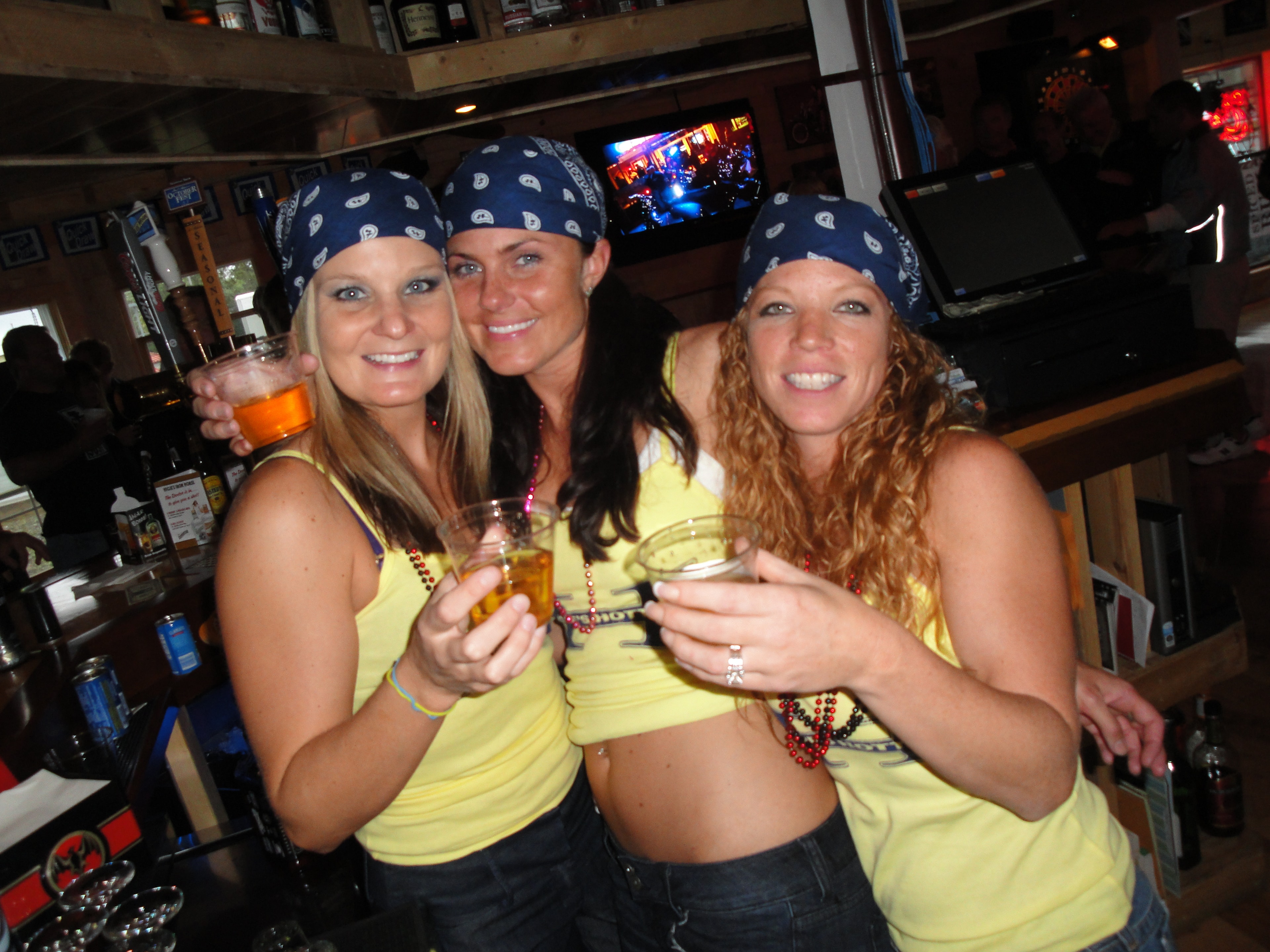 Higie's Iron Horse Saloon Summer BBQ Series — three women in yellow Iron Horse Saloon shirts and blue bandanas at the bar