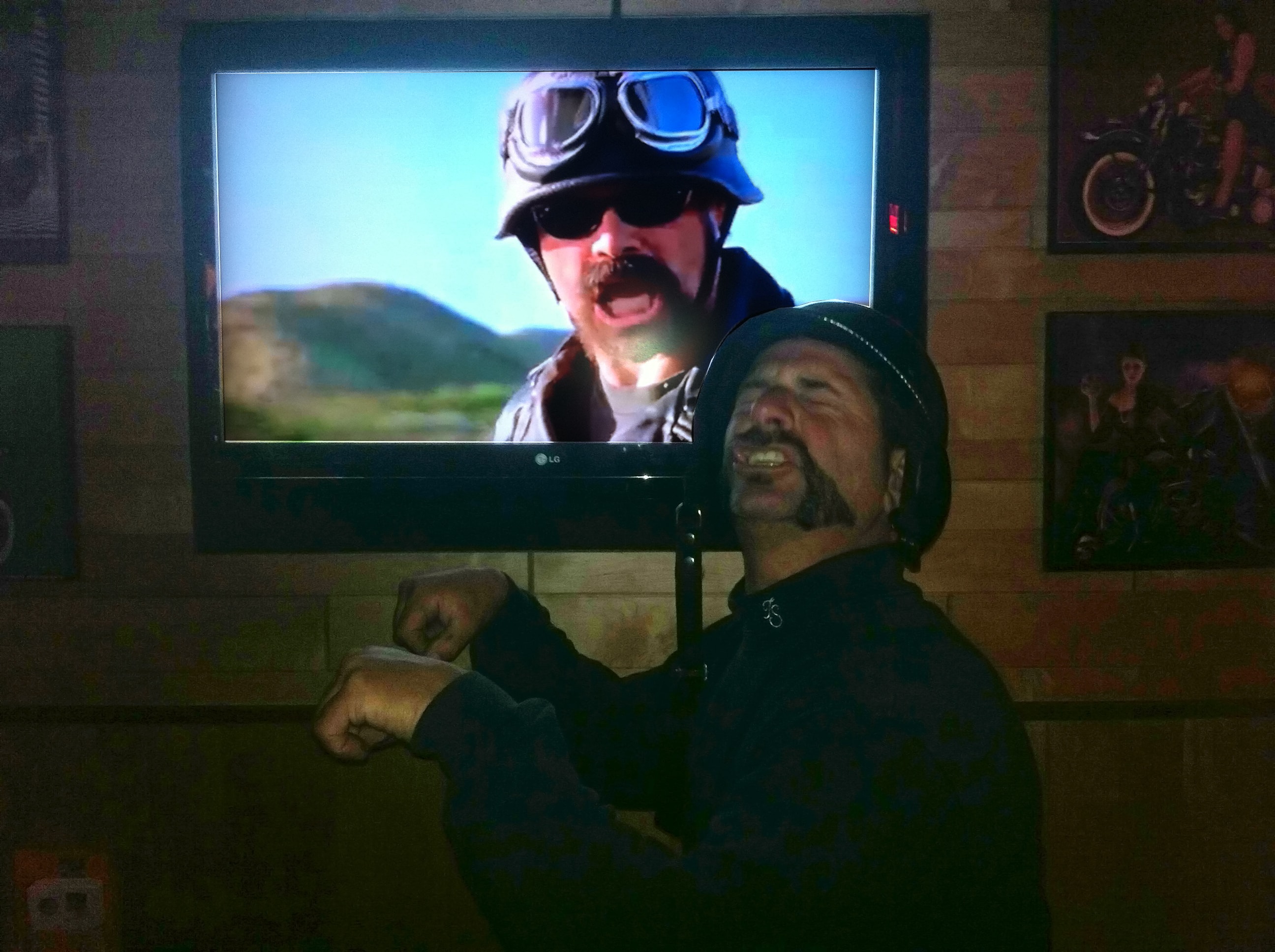Higie's Iron Horse Saloon Summer BBQ Series — man laughing in front of LG TV showing biker movie inside the saloon