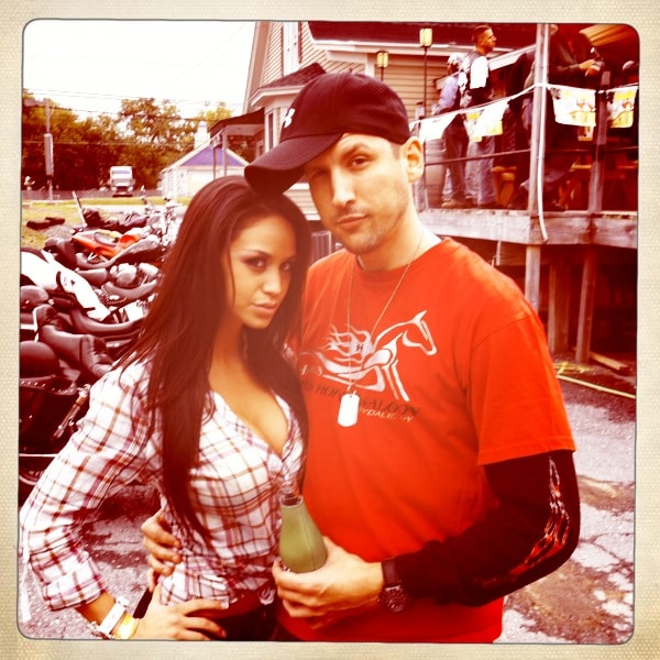 Higie's Iron Horse Saloon Summer BBQ Series — couple posing outside with motorcycles and crowd on deck behind them