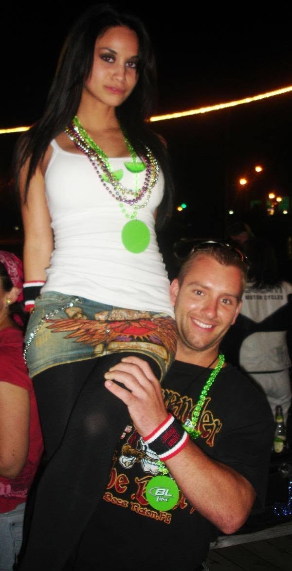 Woody's Pirate Party — woman sitting on man's shoulders with green Mardi Gras beads at night