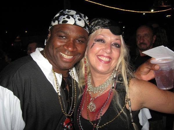 Woody's Pirate Party — man in skull bandana and pirate wench with eye patch posing together at night