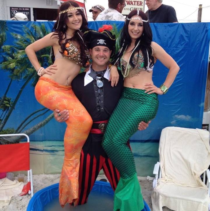 Woody's Pirate Party — pirate captain posing with orange and green mermaid performers in kiddie pool