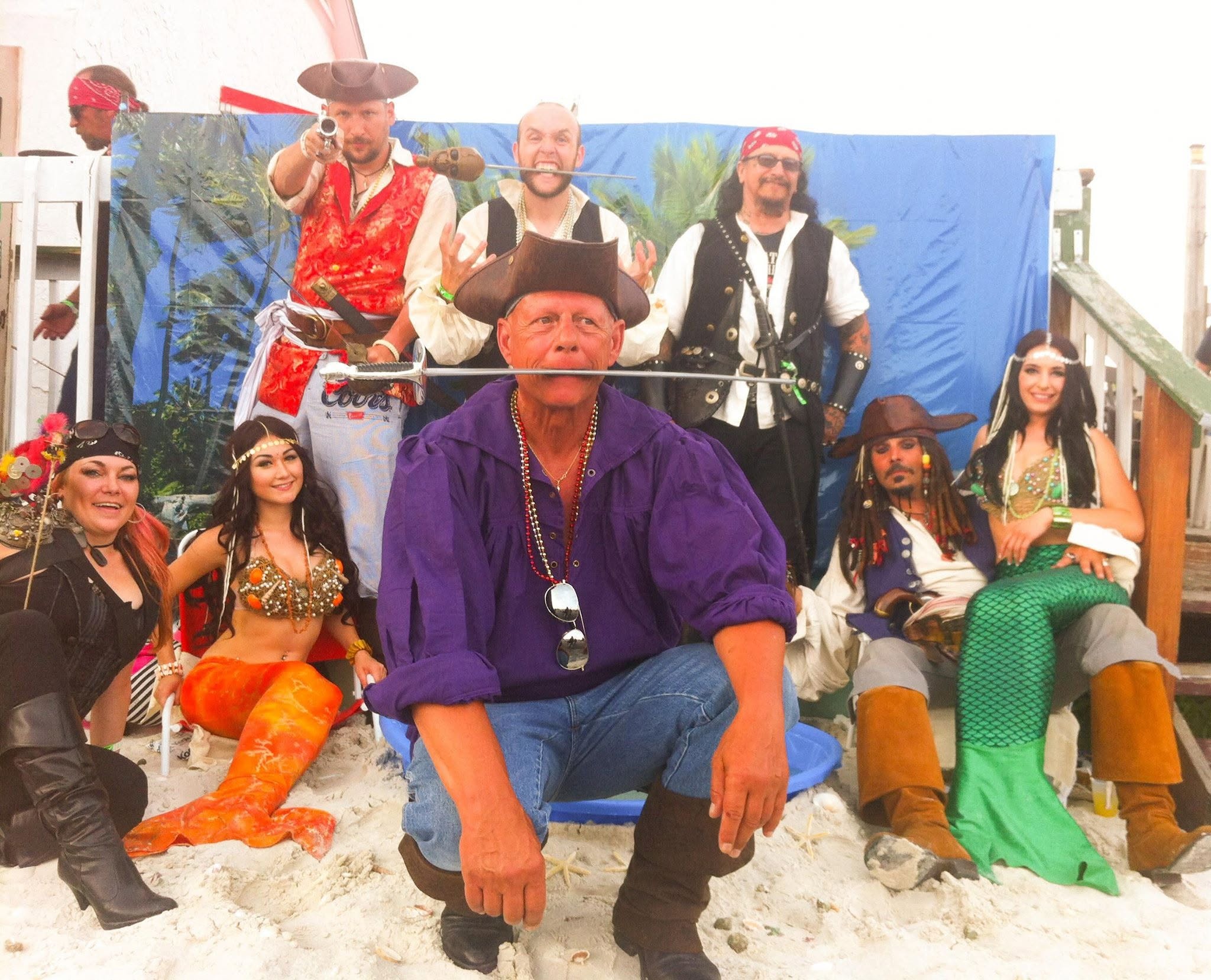 Woody's Pirate Party — six women in pirate wench and mermaid costumes posing at Woody's Jerk Pub beach set