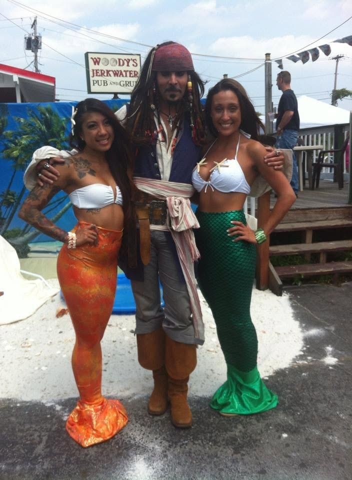 Woody's Pirate Party — man in red brocade vest pointing flintlock pistol at smiling woman with tattoo sleeve
