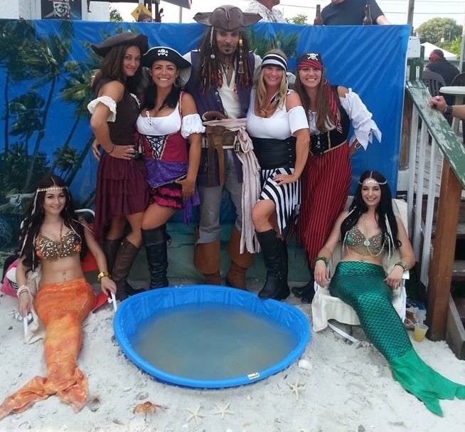 Woody's Pirate Party — Jack Sparrow lookalike with three pirate wenches and two mermaids at tropical beach backdrop