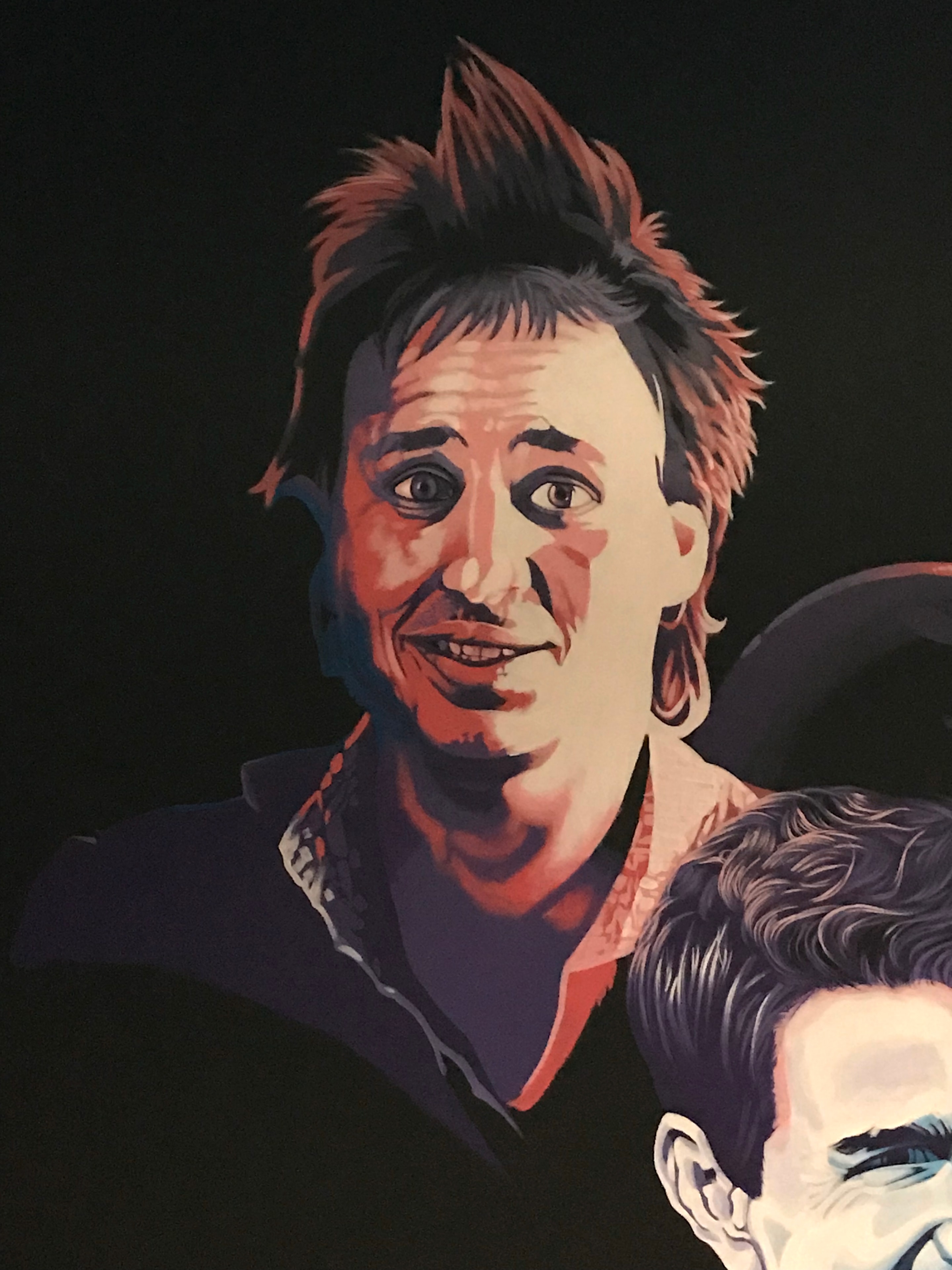 Club 11 mural detail — Bobcat Goldthwait portrait close-up with warm red and orange tones against dark background
