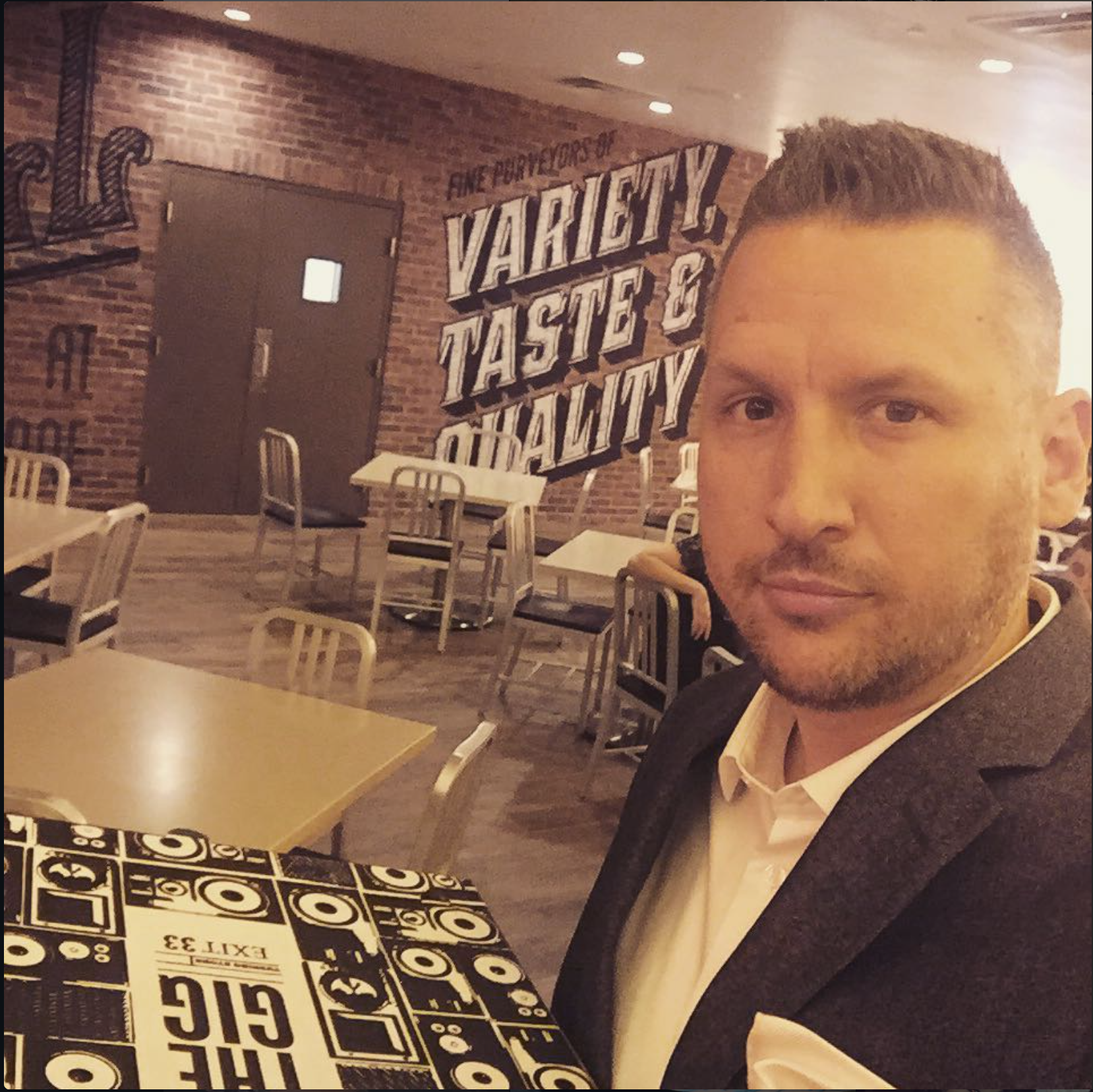 Marcus seated in the Food Hall at Turning Stone Casino with the completed "Variety, Taste & Quality" mural visible behind him