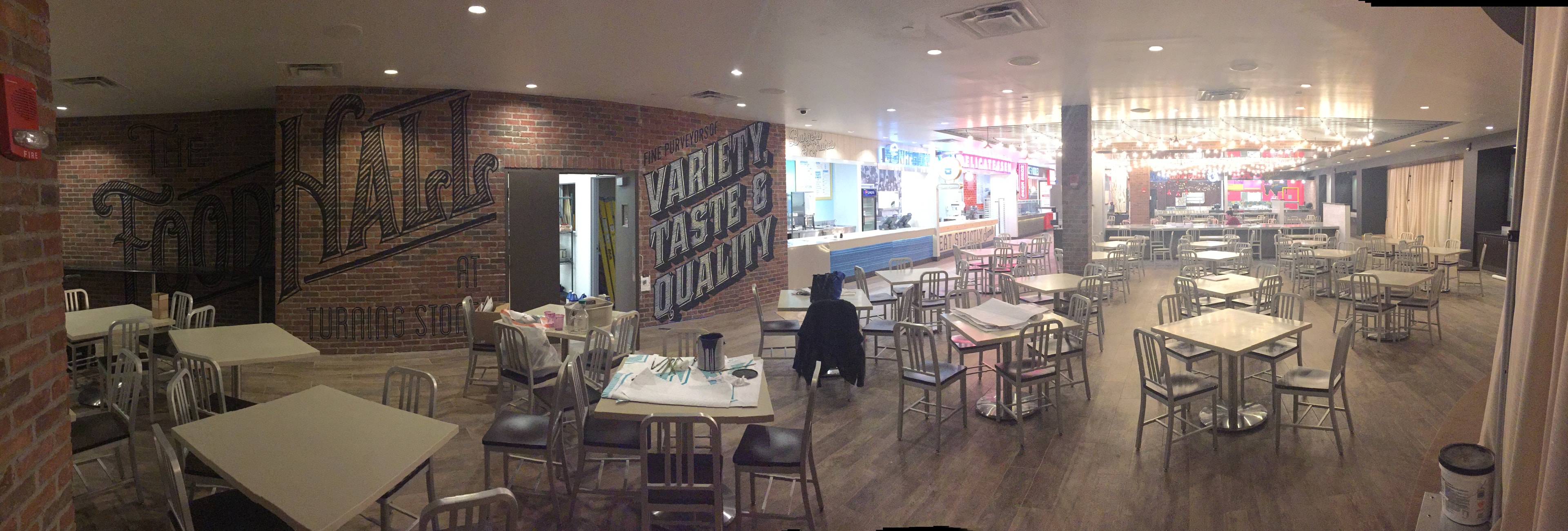 Panoramic view of the Food Hall at Turning Stone Casino — full room with mural visible on left brick wall