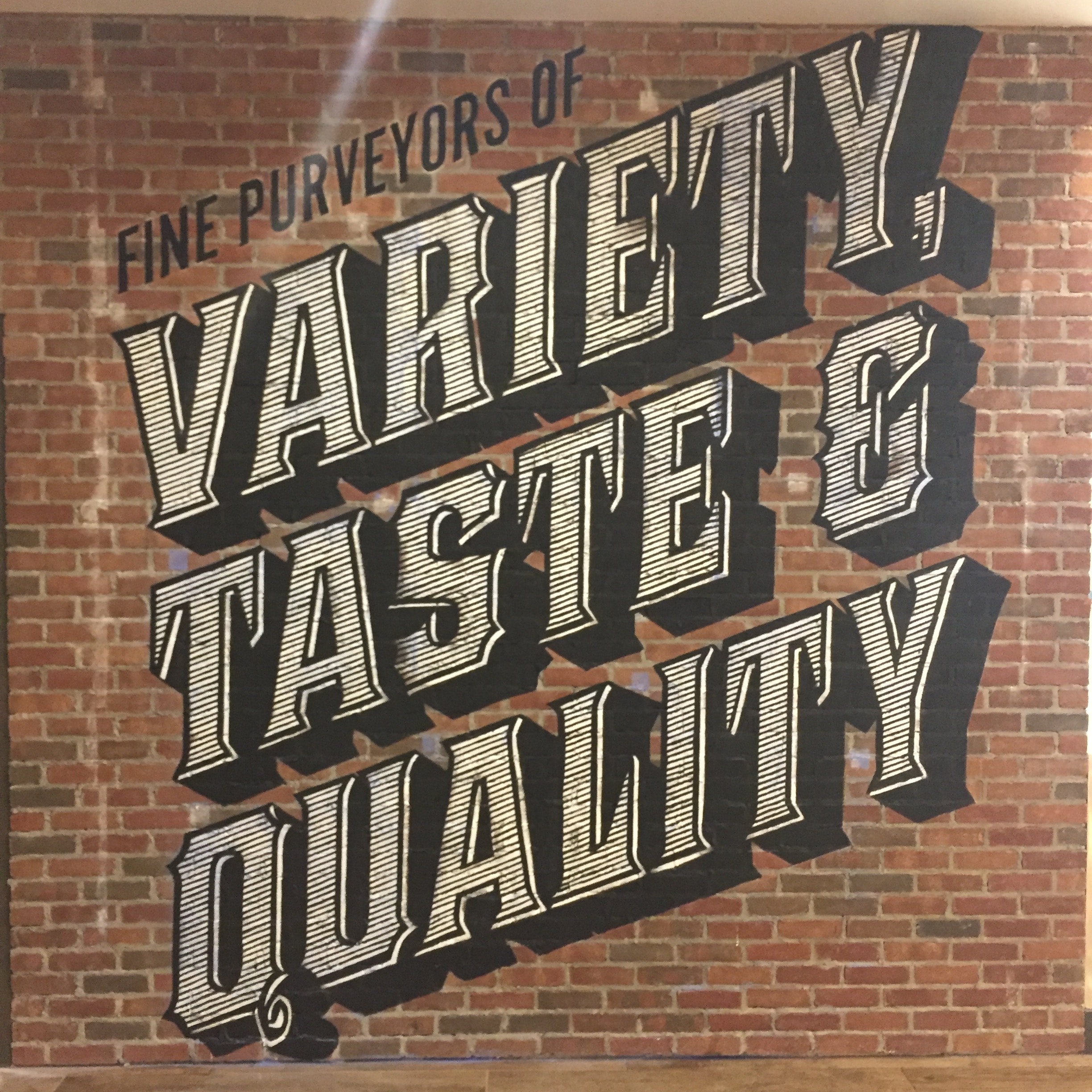 "Fine Purveyors of Variety, Taste & Quality" — bold hand-painted lettering detail on brick wall at Turning Stone