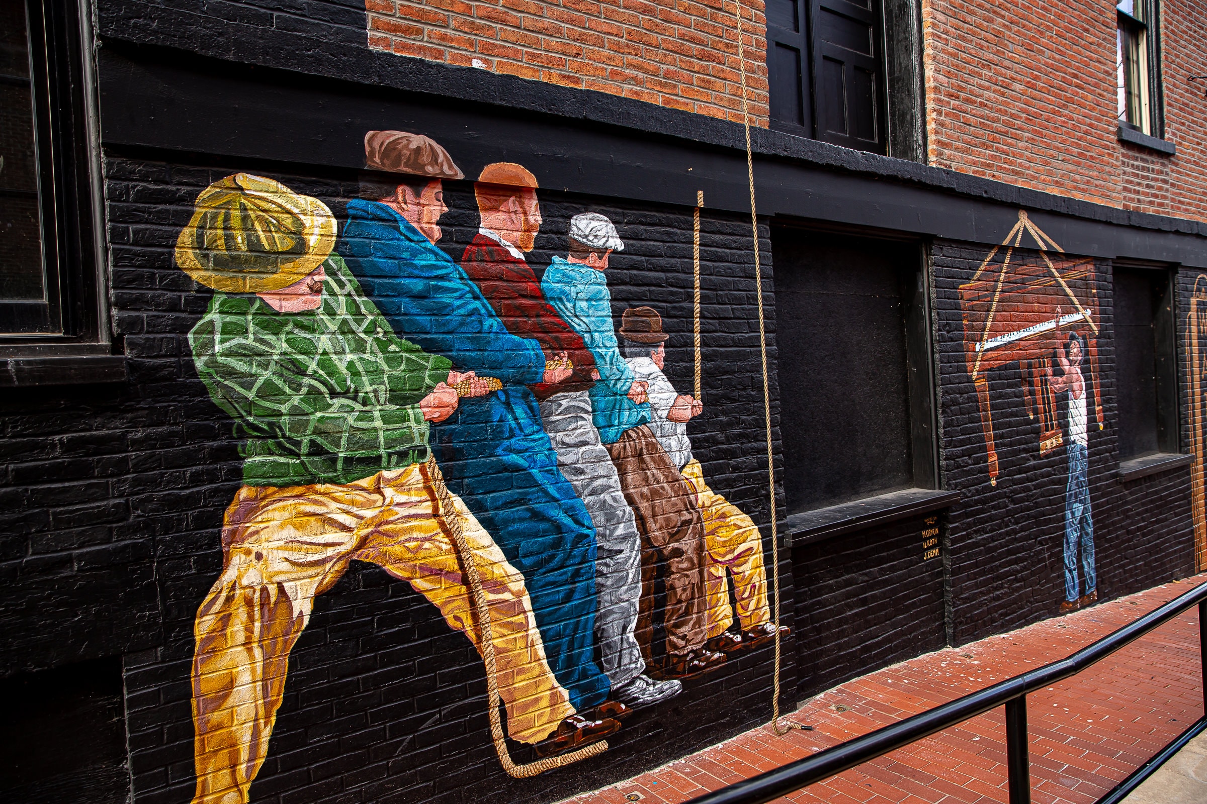 Colorful period figures on black brick wall