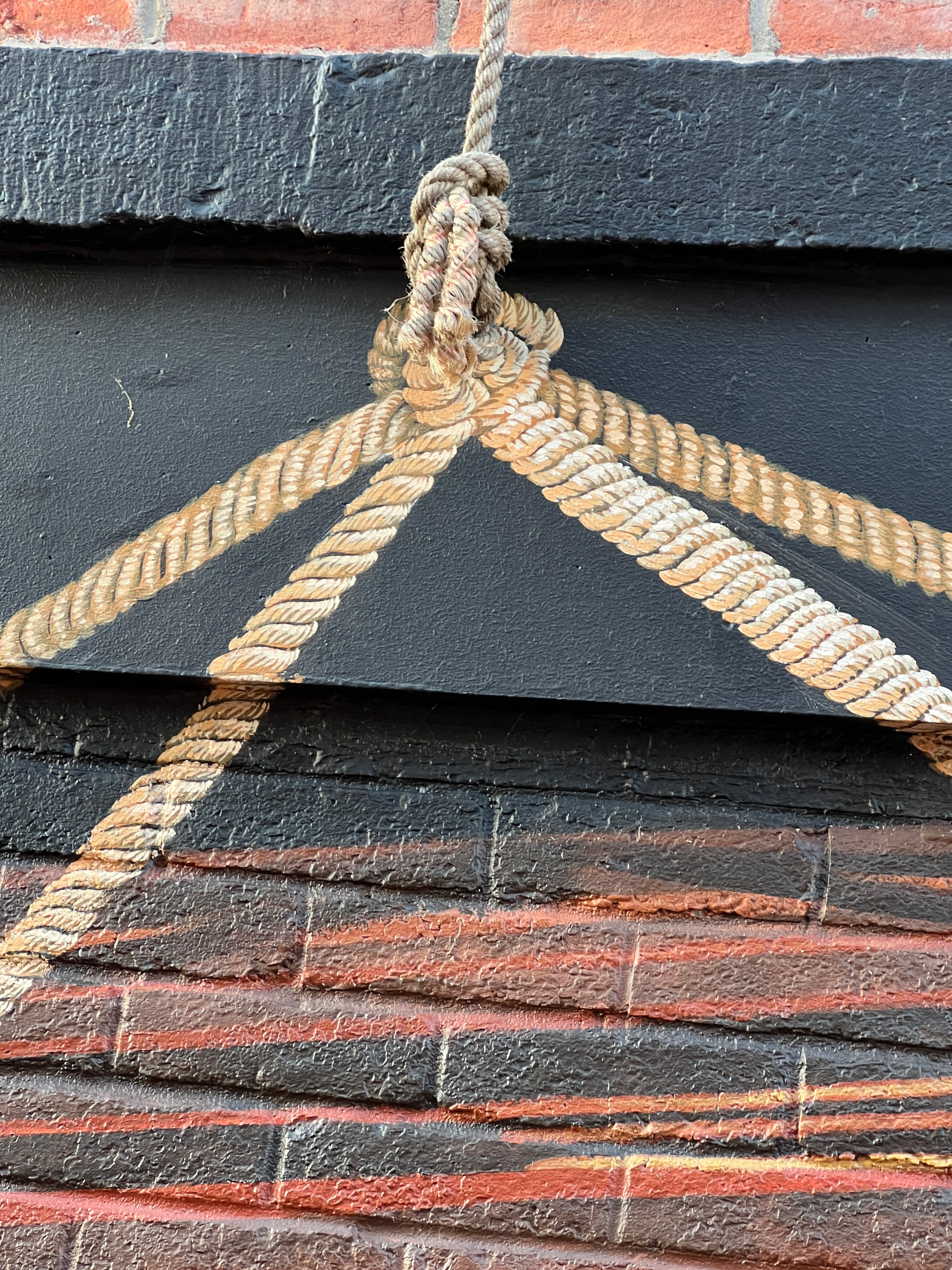 Painted rope knot — trompe-l'oeil detail on black brick