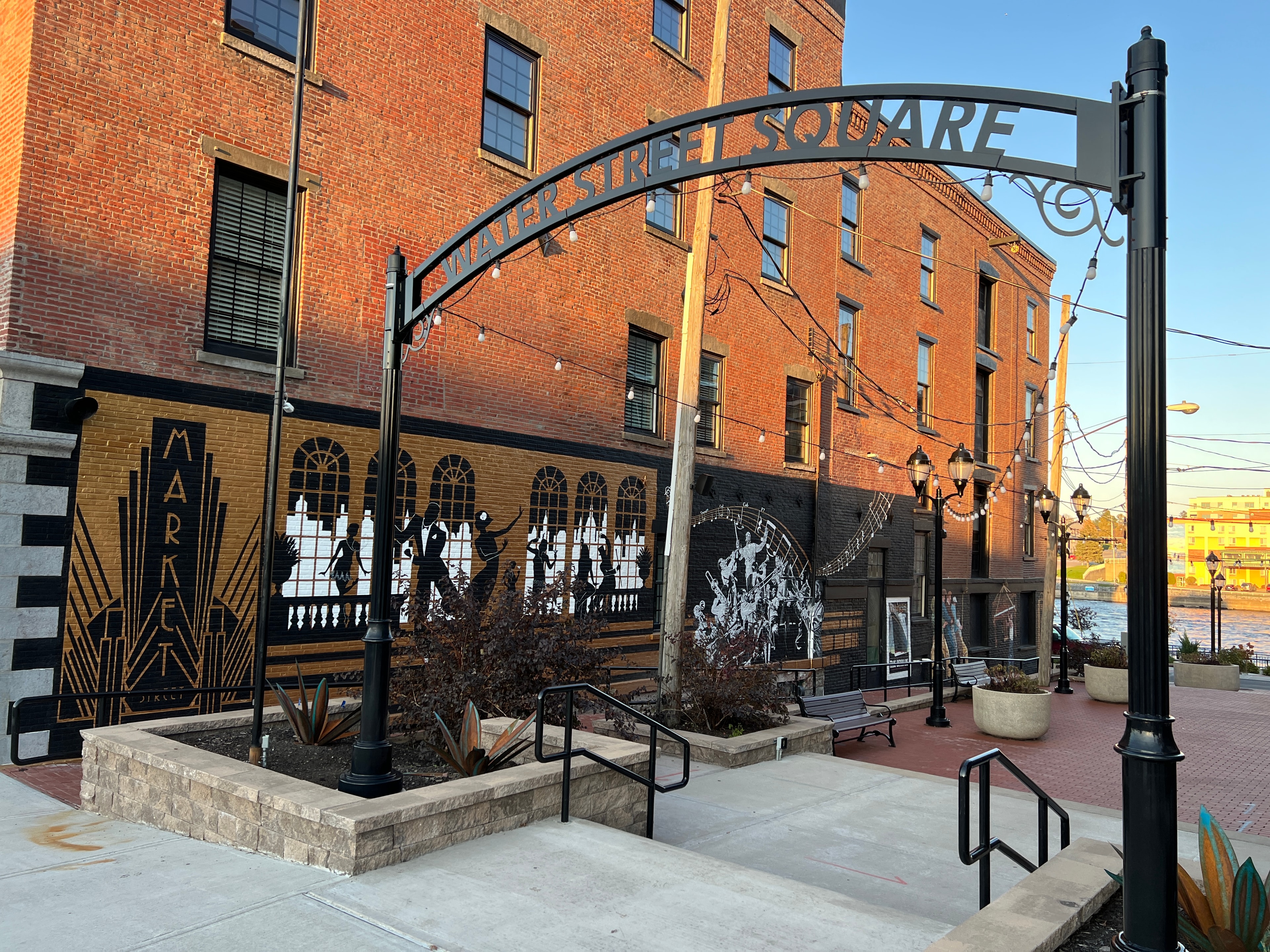 Water Street Square entrance arch with full mural complex at golden hour